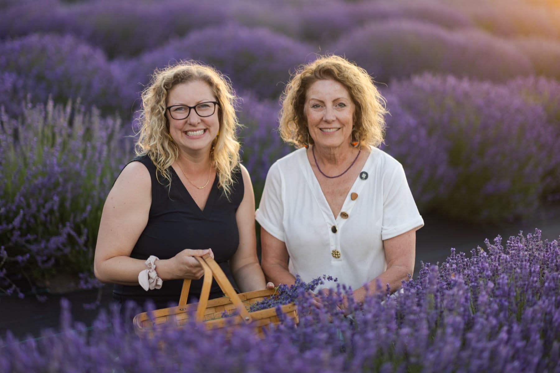 Jenny and Karen Williams holding a basket of fresh lavender in a lavender field